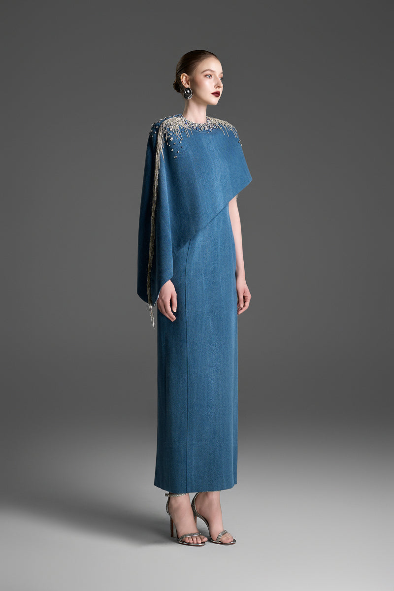 Blue asymmetrical column maxi dress with draped cape sleeve by GVLUX, featuring a sleek, elegant silhouette.