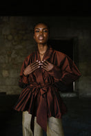 ANA + MARIA GALA Mahogany top shown in a campaign photo, featuring a stylish, fitted blouse with a V-neck and long sleeves.