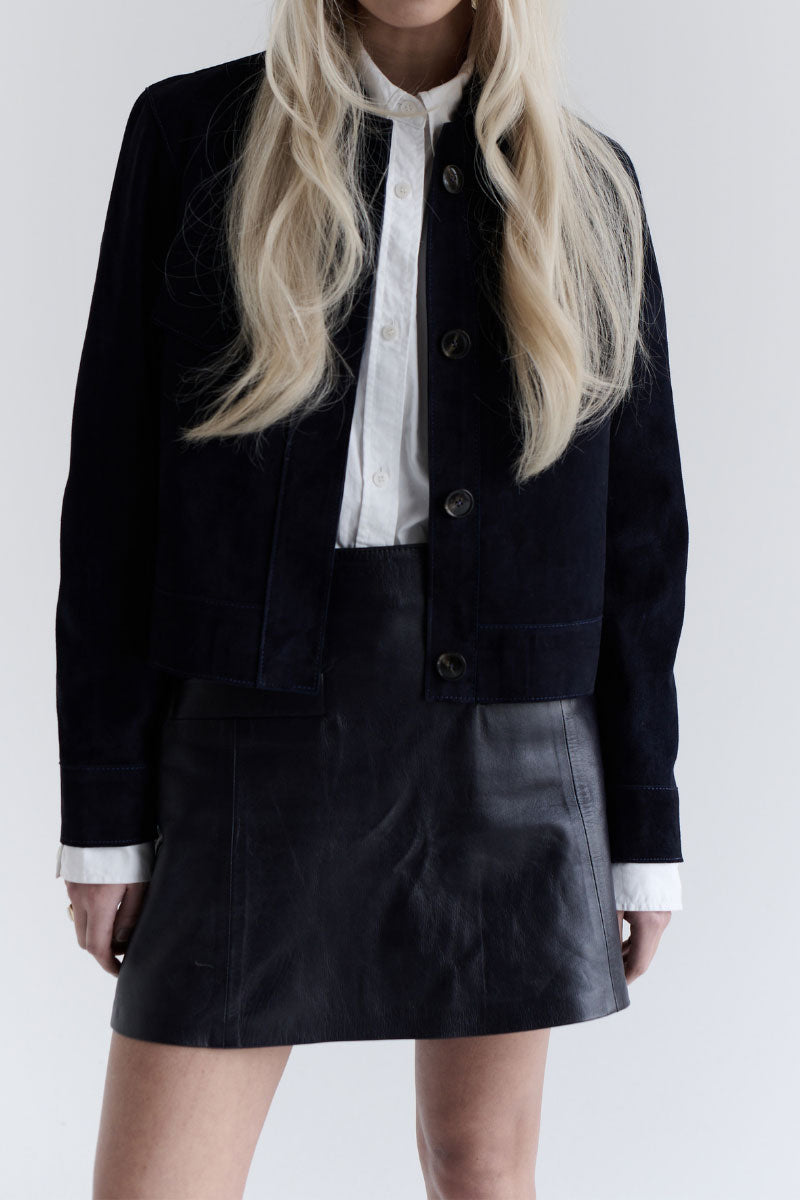Navy blue Gavea mini skirt by ZUT displayed on a hanger, showcasing its stylish fit and fabric details.