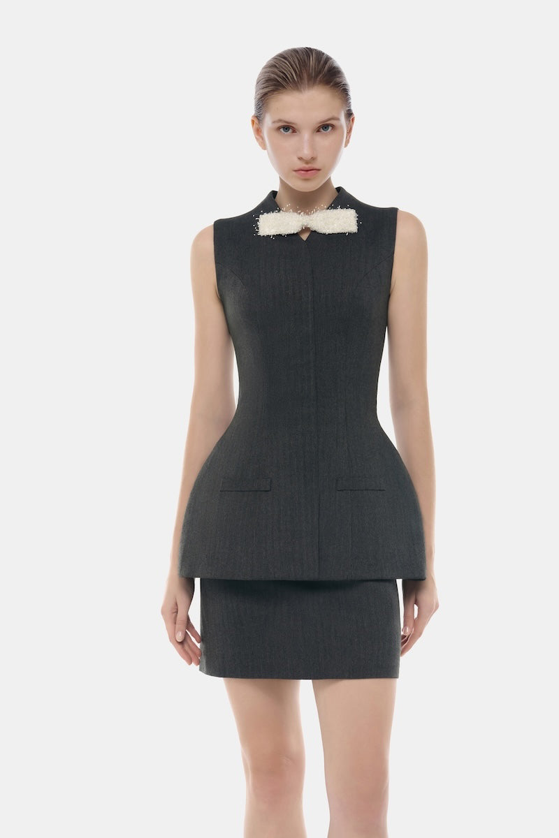 Gray sleeveless bow blazer by Montsand, featuring a tailored fit and classic design, paired with a grey tweed skirt.
