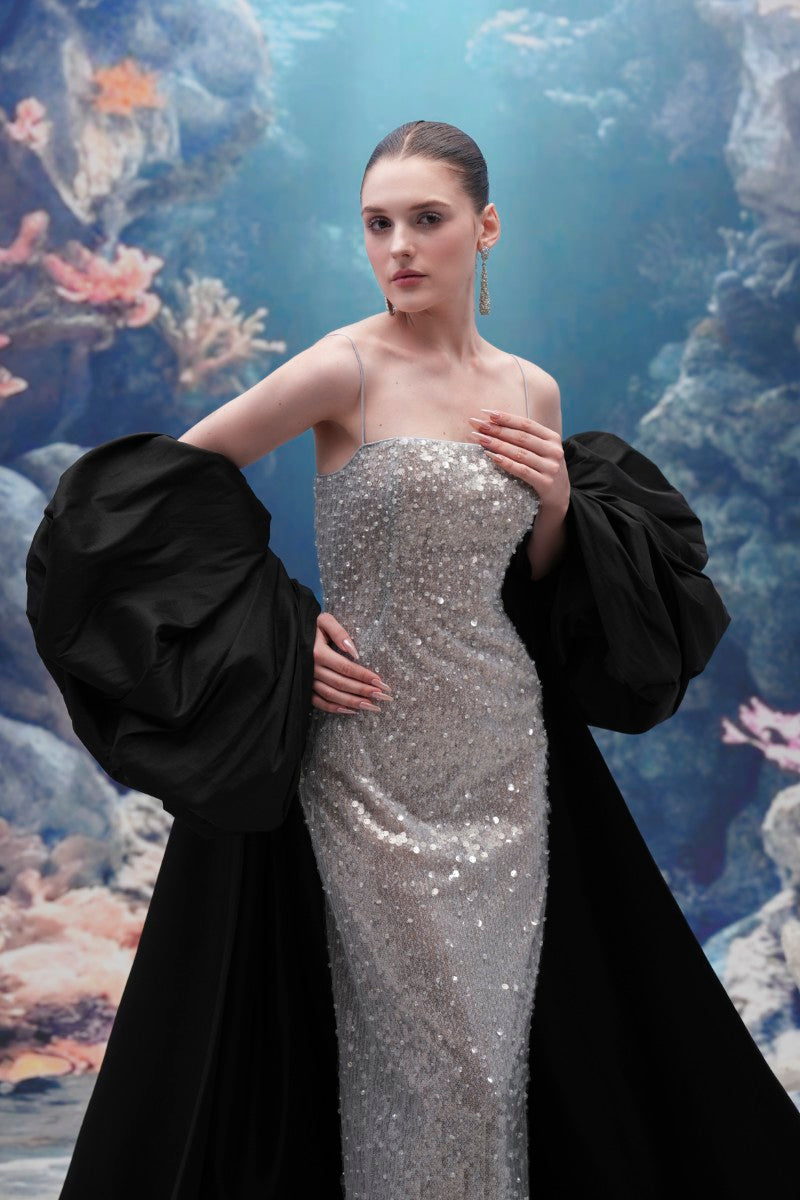 Elegant Moirae sequin gown and Marisol taffeta cape by 21Six displayed on a mannequin, showcasing luxurious evening wear details.