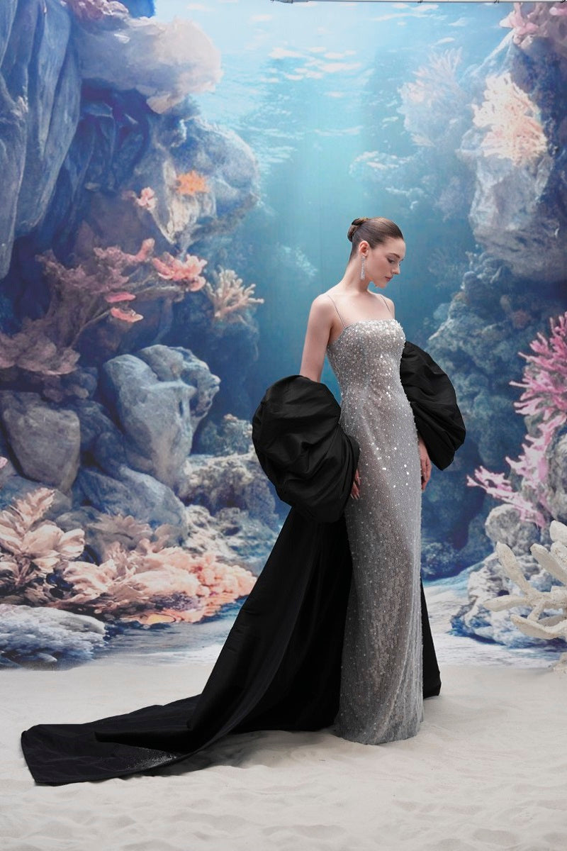 Elegant MOIRAE sequin gown paired with a Marisol taffeta cape, designed by 21Six, shown in a stylish evening wear setting.