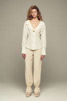 Cream Scylla pants by IKINITA featuring a relaxed fit and stylish design, shown on a model with a neutral background.