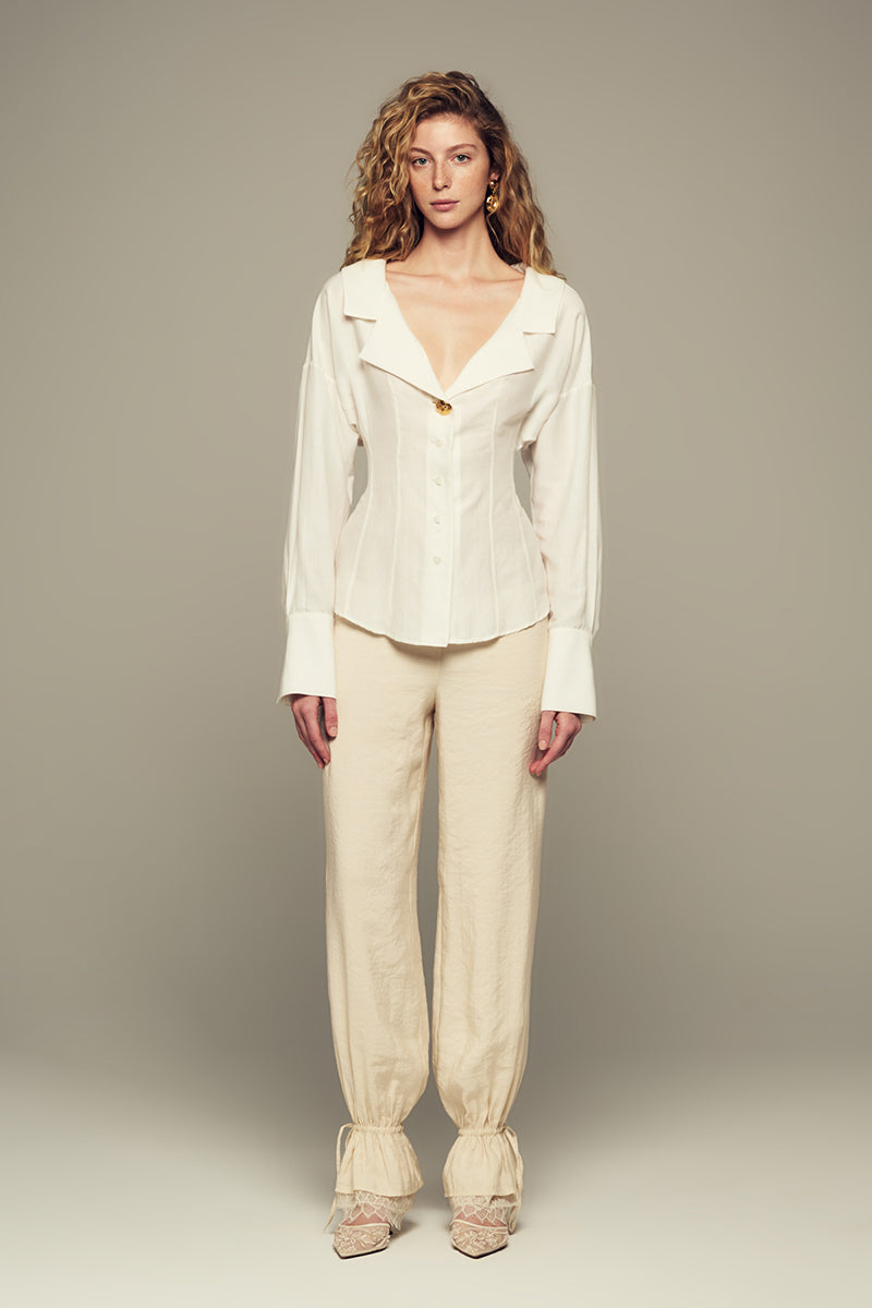 Cream Scylla pants by IKINITA featuring a relaxed fit and stylish design, shown on a model with a neutral background.