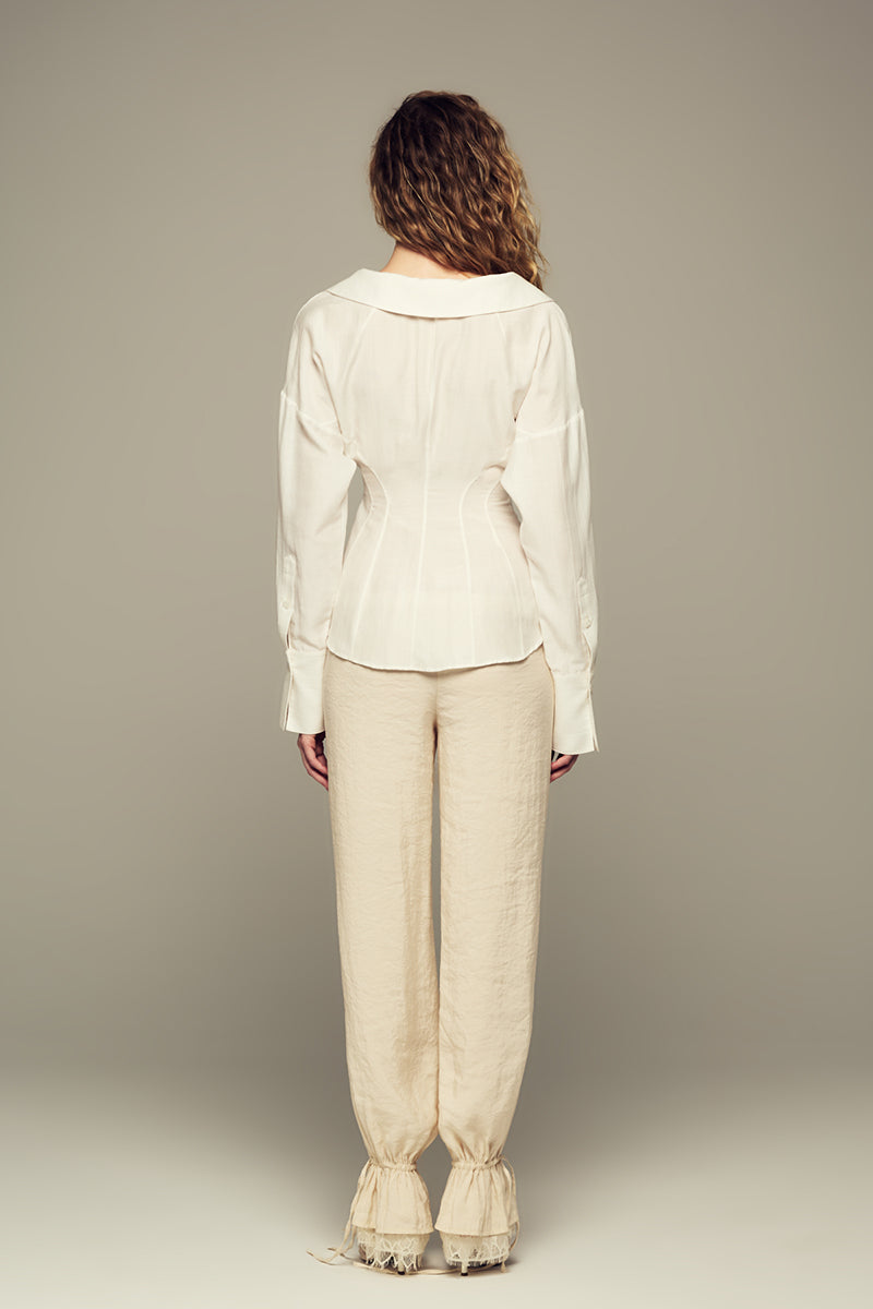 Cream SCYLLA pants by IKINITA displayed on a model, showcasing the relaxed fit and stylish design.