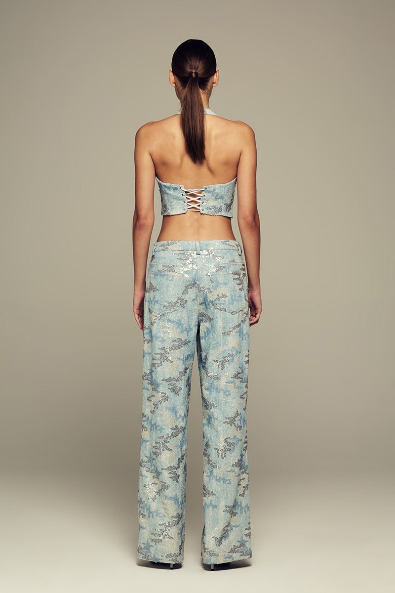 Blue IRIS pants by IKINITA, featuring a stylish fit and fabric detail, shown on a model in a casual pose.