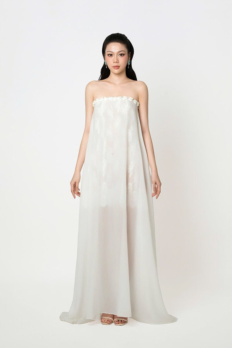 White strapless maxi chiffon dress by Valenciani, flowing and elegant, displayed on a hanger with a soft background.