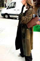 Verheyen Zina Biker Green Shearling Coat displayed on a hanger with a plush green shearling collar and stylish leather exterior.