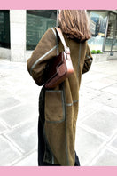 Verheyen Zina Biker Green Shearling Coat hanging on a wooden hanger with a quilted background.