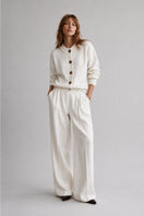 First Born Knits Frenchie Ete cardigan displayed on a hanger, showcasing its soft, lightweight knit fabric and stylish design.