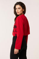 Red Señorita Rosalia jacket displayed on a hanger, showcasing its stylish design and vibrant color.