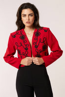 Red Señorita Rosalia jacket displayed on a hanger, showcasing its stylish design and vibrant color.