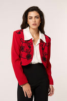 Señorita Rosalía red jacket displayed on a hanger, showcasing its stylish design and vibrant color.