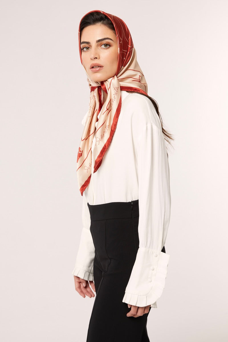 Red Señorita Luisa scarf draped over a neutral background, showcasing soft fabric and elegant design.