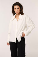 White Señorita Antonia blouse with long sleeves and button front, displayed on a hanger against a neutral background.