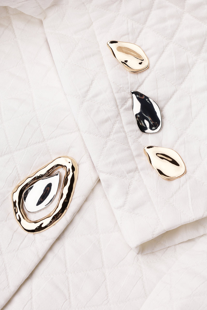 Nué Margot blazer in white, stylish tailored jacket with lapels and long sleeves, displayed on a hanger against a neutral background.