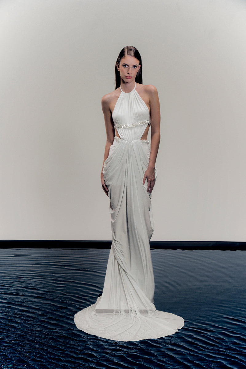 White VEYA gown by Francisco Arce, elegant floor-length dress with flowing fabric and detailed neckline, perfect for formal occasions.