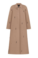 Beige rose embroidered trench coat by DELEGAN, featuring floral embroidery and classic coat design, displayed on a hanger.