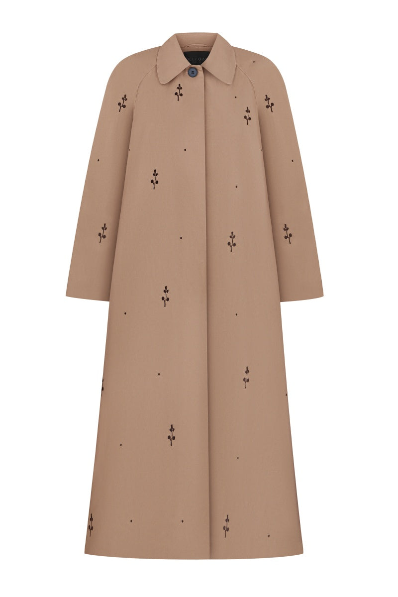Beige rose embroidered trench coat by DELEGAN, featuring floral embroidery and classic coat design, displayed on a hanger.
