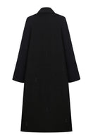 Black trench coat by Delegan, shown on a hanger with a classic double-breasted design and belt details, full-length view.