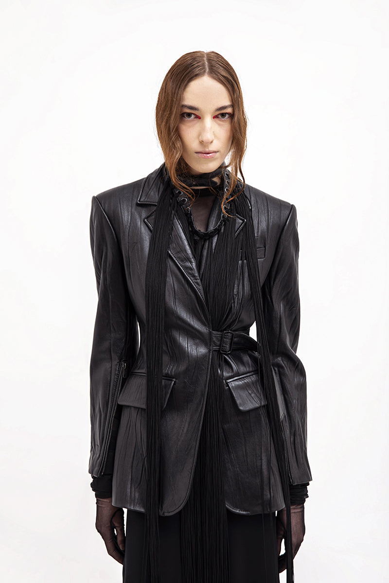 Black textured leather jacket by Vaska, shown in a close-up image highlighting the detailed leather surface and stylish design.