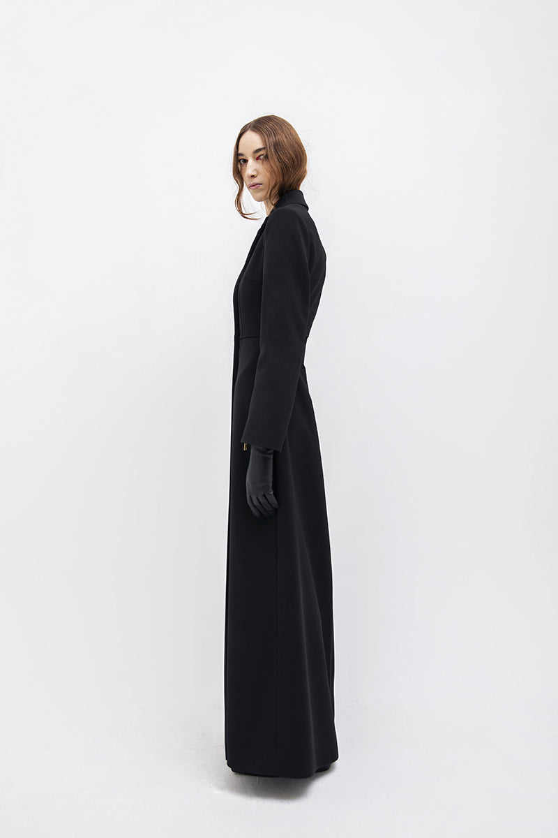 Black Vaska long trench jacket with zippers, featuring a sleek design and modern style, shown on a model.