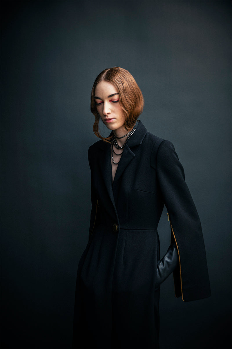 Vaska black long trench coat with zippers, stylish and modern jacket shown in the image.