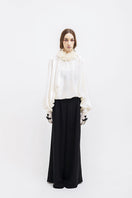 Black Vaska wide-leg pants with belted waist, featuring a relaxed fit and stylish design, shown on a model.