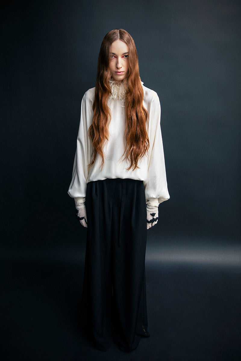 Black wide-leg pants with belted waist from Vaska, showing the relaxed fit and stylish waistband detail.