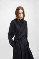 Black Vaska wide leg pants displayed on a hanger, showcasing their relaxed fit and flowy fabric.