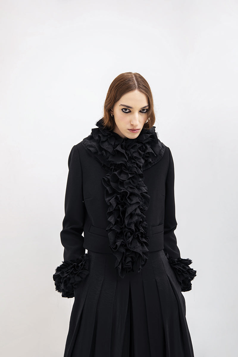Black Vaska crop jacket with ruffles, featuring a stylish design and feminine details, perfect for a trendy layered look.