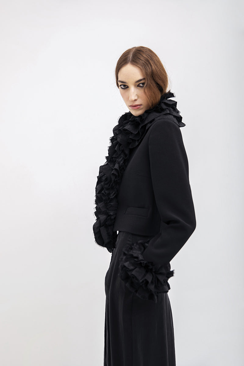 Black Vaska crop jacket with ruffles, stylish women's jacket featuring a fitted design and ruffle detailing on the sleeves.