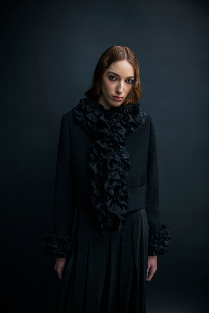 Black oversized blazer by Vaska featuring intricate beaded embroidery, displayed on a hanger with a neutral background.