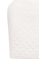 White Nué Margot mini skirt displayed on a model, showcasing its fitted design and stylish silhouette.