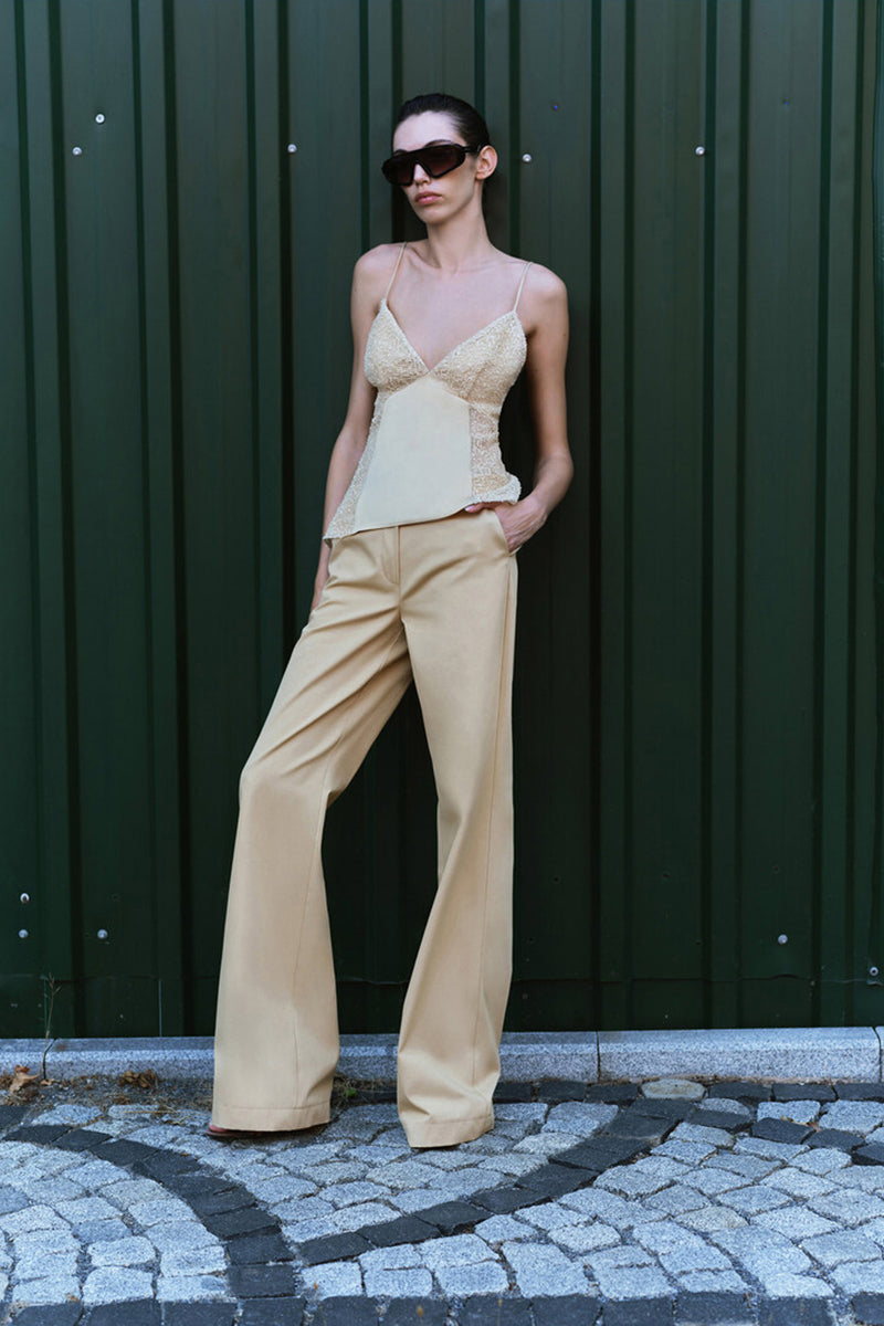 Beige ILA Jenny Pants with tailored fit, shown on a model, featuring a high waist and straight-leg design.