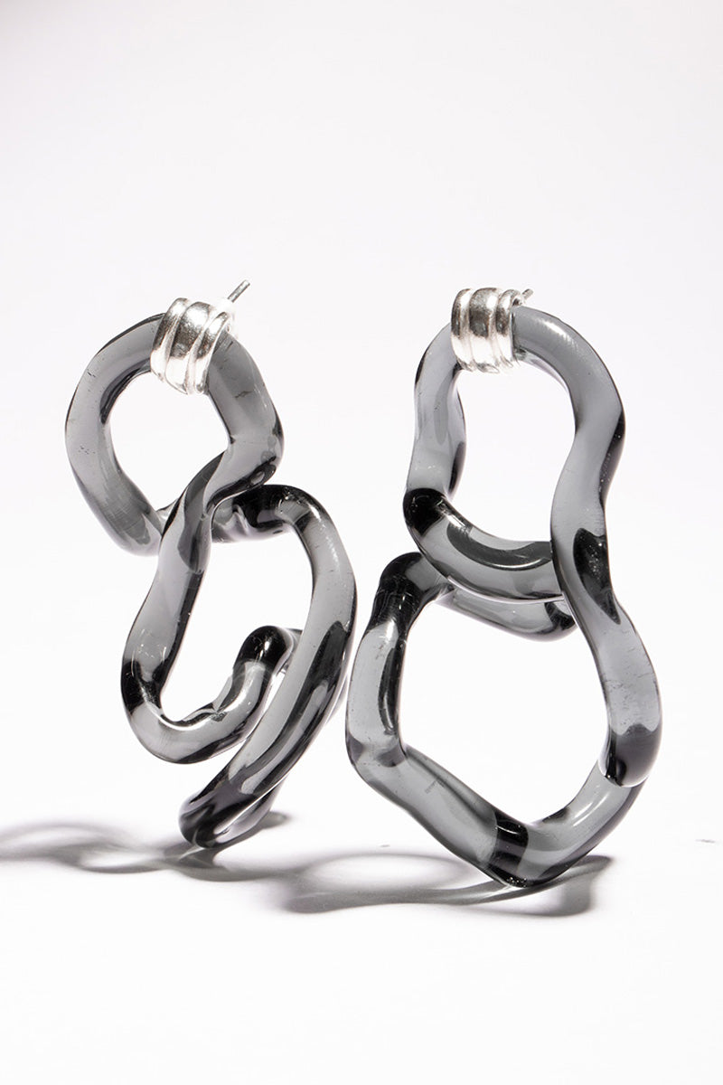 Salvárea Interconexión L earrings in smoke-colored acrylic with geometric design on a white background