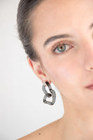 Salvárea Interconexión M earrings in smoky design, featuring modern, interconnected metal loops on a white background.