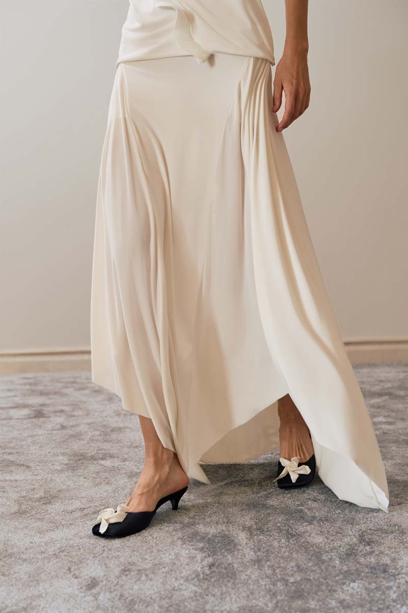 Close-up of YASSMIN SALEH ivory intersect midi skirt showing textured fabric and subtle design details.