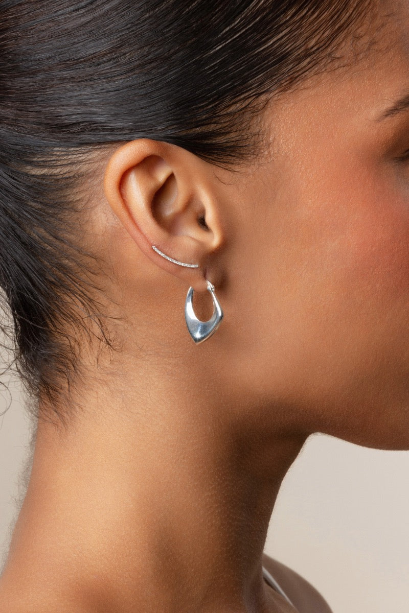 Silver hoop earrings by Sara Shala featuring sleek, polished hoops worn by a model.