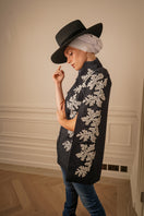 Nadya Shah Iris Denim Cape jacket displayed on a hanger, featuring classic denim fabric with a stylish cape design.