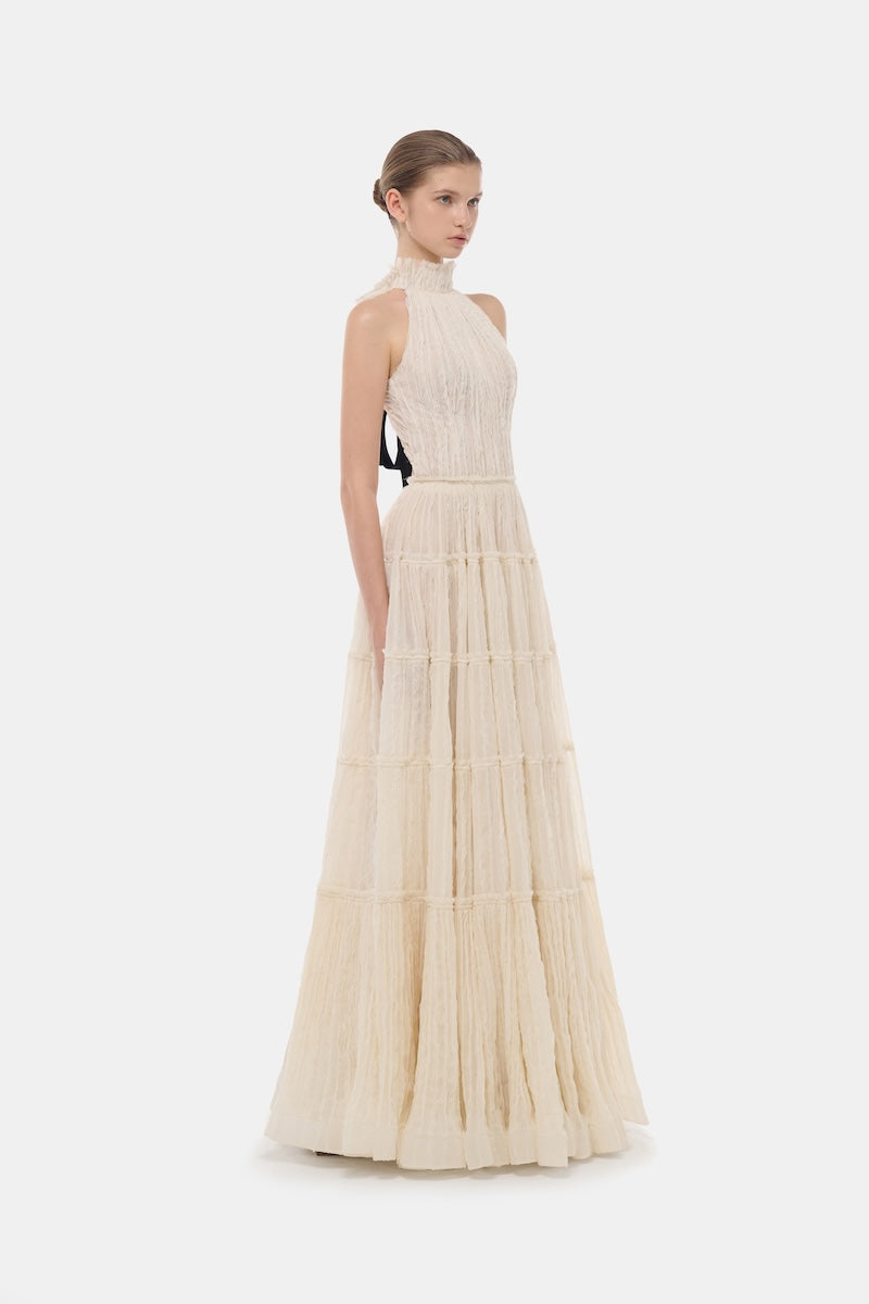 Elegant ivory tiered halter gown by Montsand featuring flowing fabric and a stylish, layered maxi design.