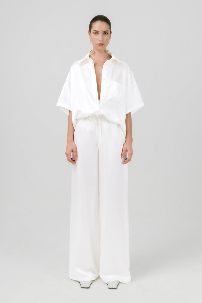 White Melanie pants by Izakova, showcasing a stylish, tailored fit with smooth fabric and classic design on a model.