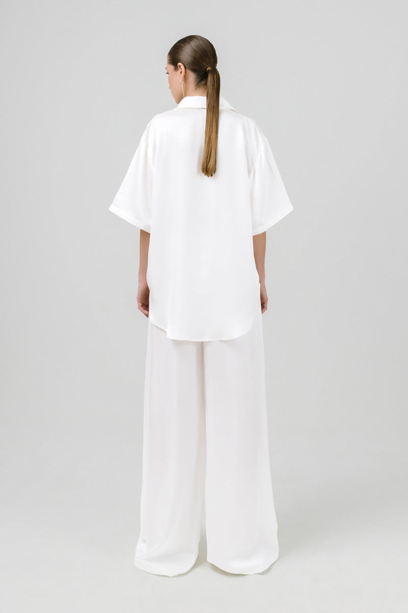 White Melanie pants by Izakova featuring a relaxed fit and stylish design, displayed on a model.