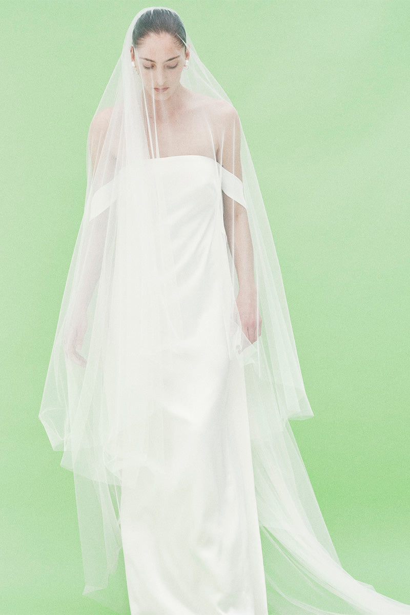 Elegant strapless satin maxi dress by JC Pajares shown in a bridal campaign look, featuring a flowing silhouette and luxurious fabric.