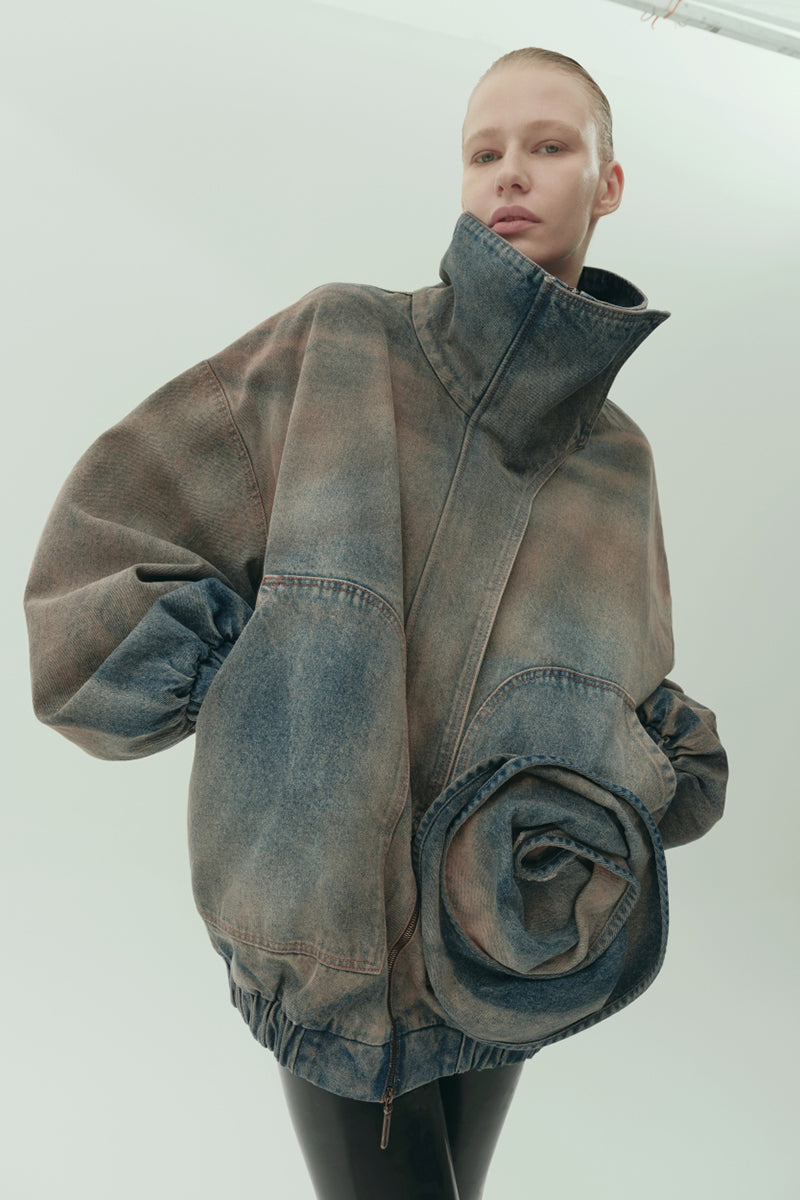 Model wearing NADYA DZYAK oversized denim bomber blazer with a funnel neck in rusty denim, styled for a modern, relaxed look.