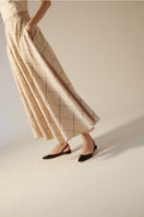 A pair of AERA Jackie black patent-effect slingback flats on a white background, showcasing the sleek and shiny design.