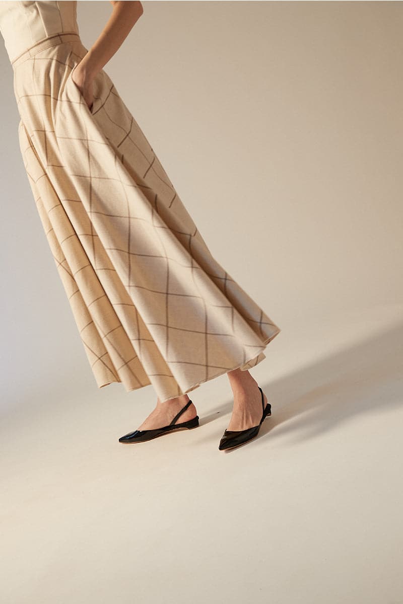 A pair of AERA Jackie black patent-effect slingback flats on a white background, showcasing the sleek and shiny design.