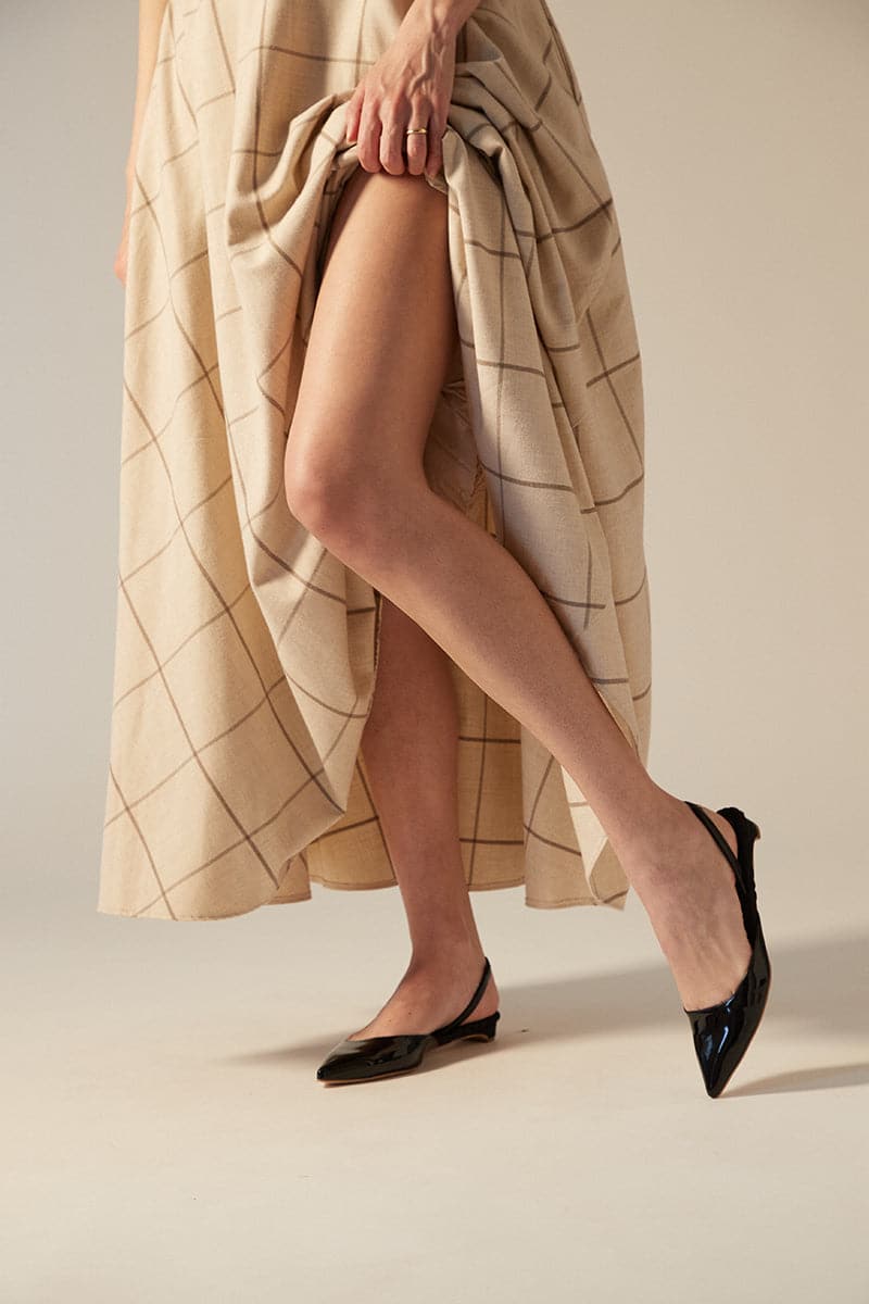 A pair of AERA Jackie black patent-effect slingback flats with pointed toes and sleek design, shown from a side angle.