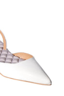 A pair of ivory patent-effect slingback flats from AERA, showcasing their sleek design and front view.