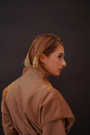 Nadya Shah Jules Ecru belted jacket featuring a tailored fit, with a classic collar and side pockets, displayed on a hanger.